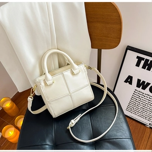 Détail du sac seau blanc en similicuir avec motif en treillis sur une chaise noire