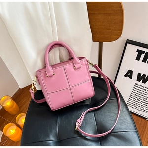 Détail d'un sac seau en cuir PU rose vif avec coutures en treillis et ferrures dorées