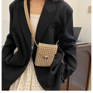 Dettaglio mini borsa cammello con strass e fibbia in metallo argento su abito nero