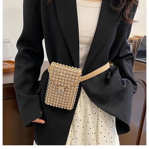 Elegante marsupio con strass indossato sopra un blazer con texture lucida e fibbia