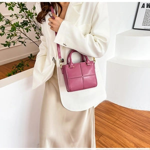 Détail du sac bandoulière matelassé magenta avec garniture dorée porté sur une veste blanche