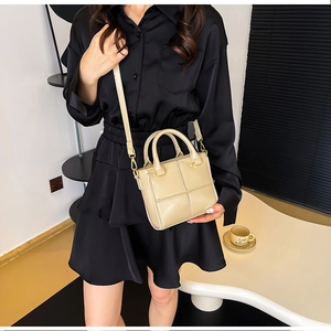 Détails du sac seau beige avec coutures géométriques et finitions métalliques dorées