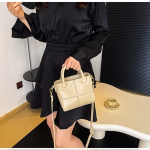 Détail du sac seau beige crème avec surpiqûres quadrillées et garnitures en métal doré