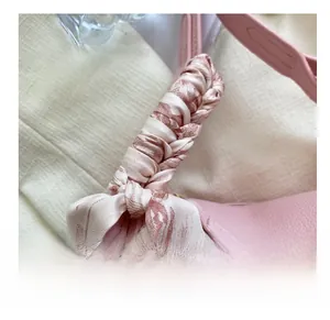 Detail van roze lederen tas met gouden gesp en decoratieve zijden sjaal aan het handvat