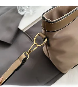 Detail of sturdy golden D-ring and lobster clasp on a khaki nylon tote bag