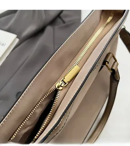 Detail shot of smooth golden metal zipper and black edge paint on khaki nylon bag