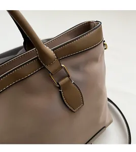 Close-up of golden hardware and leather strap stitching on a nylon tote bag