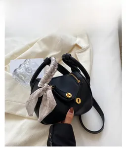 Détail d'un sac bandoulière noir en cuir grainé avec foulard en soie et boucle dorée