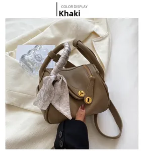 Détail du sac en cuir grainé kaki avec fermoir doré et poignée ornée d'un foulard