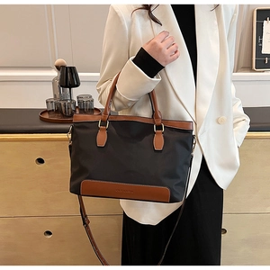 Sac fourre-tout chic en nylon noir avec anses en cuir marron porté avec un blazer blanc