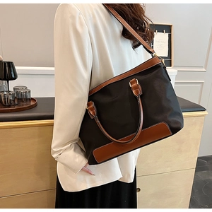 Detail of the high-capacity nylon and leather tote bag showing crossbody strap and textures