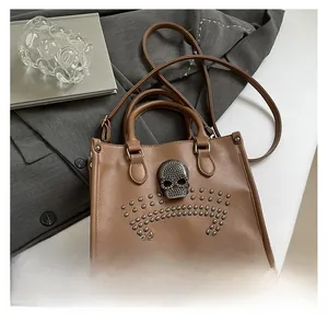 Close-up of brown leather bag with silver skull stud and rivet details on office desk