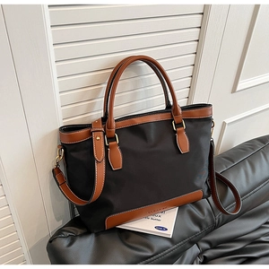 Détail du sac cabas en nylon avec finitions en cuir et boucles dorées en noir et marron