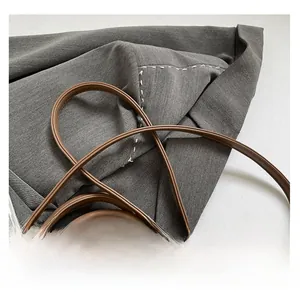Detail of brown leather shoulder strap with metallic buckle and contrast stitching