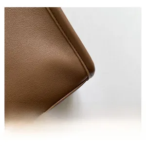 Macro view of brown leather texture and stitching detail on the bag's corner