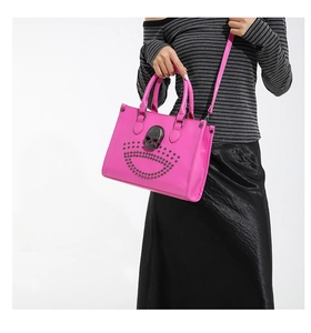 Macro view of metallic skull ornament and silver rivet details on magenta leather tote