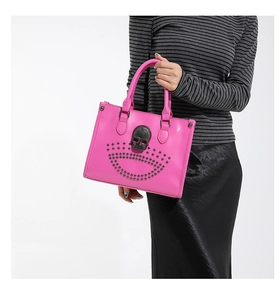 Detail of rose pink tote bag with black skull charm and studs on shiny leather