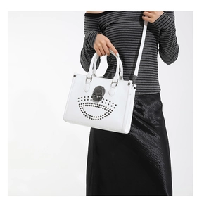 Detail of white gothic tote bag featuring metallic skull emblem and silver rivets detail