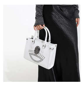 Sac fourre-tout blanc punk avec crâne et rivets porté comme sac à épaule élégant