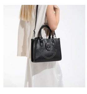 Detail of black leather tote bag with rhinestone skull motif and silver metal rivets
