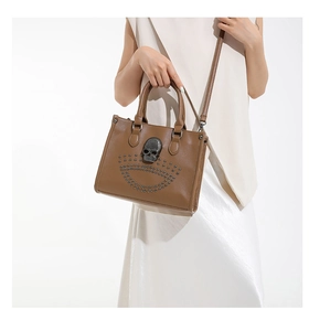 Macro shot of gothic brown tote with 3D skull badge and metallic rivet details