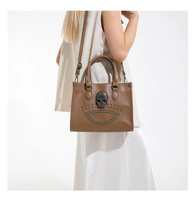 Detail of gothic dark brown tote bag with silver skull stud decor on a model