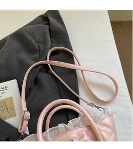 Detail of adjustable long shoulder strap on pink quilted crossbody basket bag