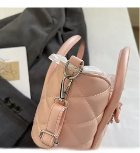 Detail view of silver hardware lobster clasp and pink quilted pattern on shoulder bag