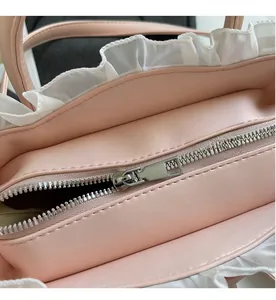 Close-up of pink quilted leather bag featuring white lace trim and smooth silver metal zipper