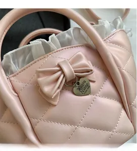Close-up of pink quilted handbag featuring a sweet bow, metal heart tag and white ruffle trim
