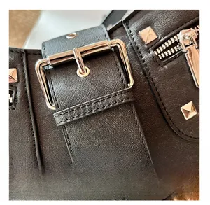 Macro shot of black textured leather with silver square rivets and a bold metal buckle