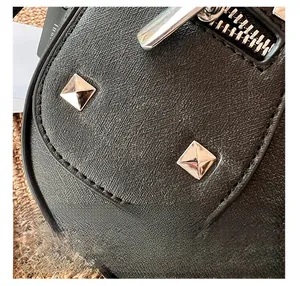 Close-up of black textured leather bag featuring silver square studs and metal zipper details