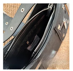 Detail view of smooth zipper closure and interior pocket on black faux leather baguette bag