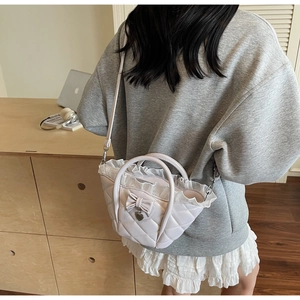 Detail of lavender quilted bucket bag with lace trim, bow, and heart charm accessory