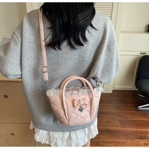 Detailed back view of a pink quilted shoulder bag with lace trim and heart charm