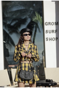 Detail showing a black crescent bag with silver studs worn with a yellow plaid outfit
