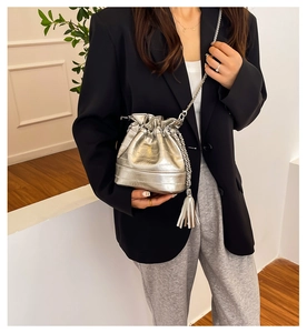 Silver bucket bag with crocodile texture, metal chain strap and tassel charm detail