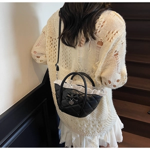Quilted black handbag with heart charm and ruffle trim detail shown on a model