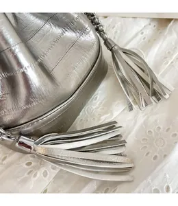 Close-up of silver crocodile embossed bucket bag with leather tassel and chain strap