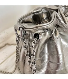 Close-up of silver quilted bucket bag with drawstring closure and metal chain strap