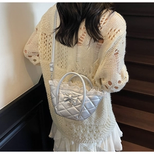 Close-up of silver quilted bucket bag with bow, lace trim, and heart charm detail