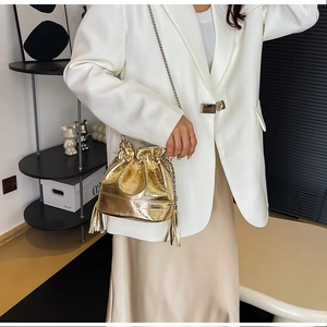 Dettaglio di una borsa a secchiello oro metallizzato con coulisse e nappe a frangia
