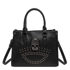 Black leather tote bag with crystal skull and metal studs on white background