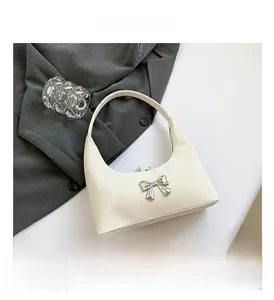 Close-up of cream PU leather shoulder bag featuring a silver metallic bow decoration