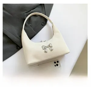 Detail of hobo bag with silver bow accent showing scale next to a mobile phone