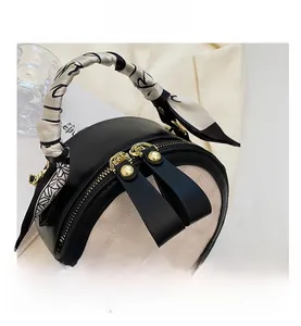 Détail du sac rond matelassé avec double fermeture éclair et poignée en foulard de soie