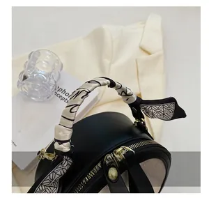 Détail du sac en cuir noir avec anse foulard en soie et double zip doré