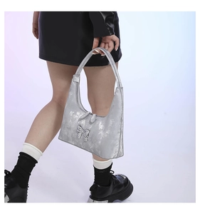 Detail of silver metallic PU handbag featuring a 3D bow and textured finish for women