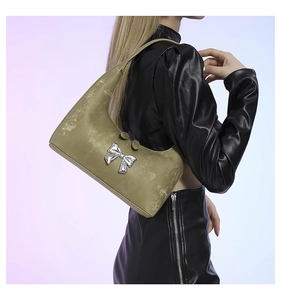 Detailed shot of olive green velvet shoulder bag with a silver metallic bow decoration