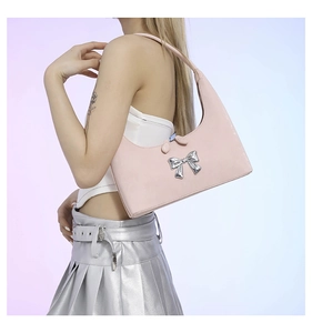 Close-up of pink PU leather shoulder bag with metallic silver bow detail in Y2K style